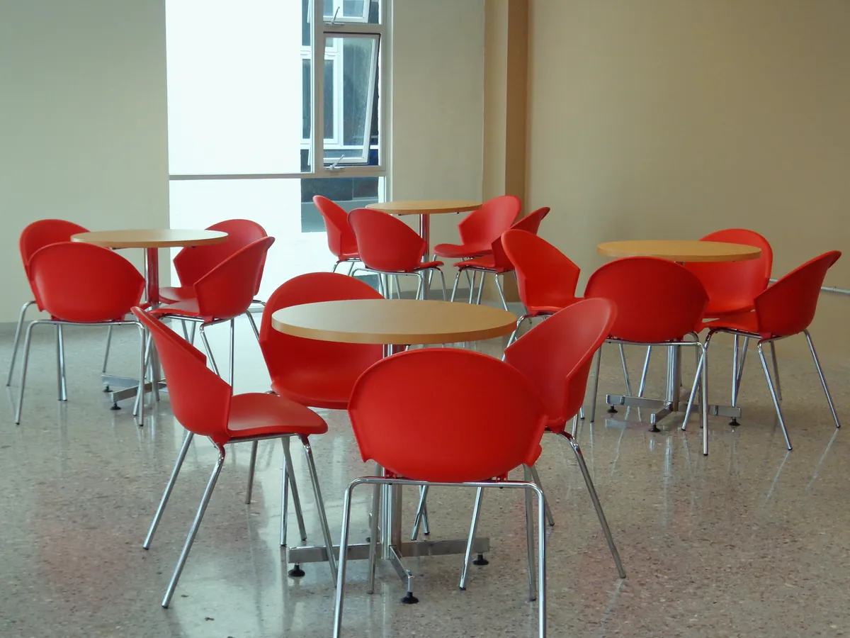 Comedor con sillas rojas y mesas redondas de madera