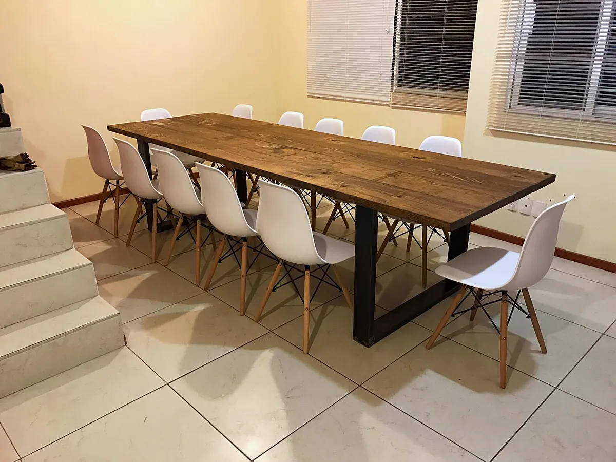 Mesa de madera con base metálica y doce sillas blancas