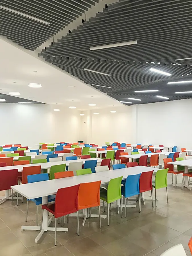 Comedor amplio con mesas blancas y sillas de colores