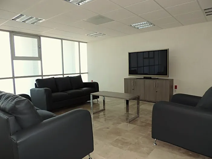 Sala de espera con sillones negros y mesa de centro